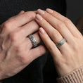 Load image into Gallery viewer, Oxidized sterling silver hammered band worn on finger, rugged lava-like texture with dark recessed detailing, lifestyle hand close-up.
