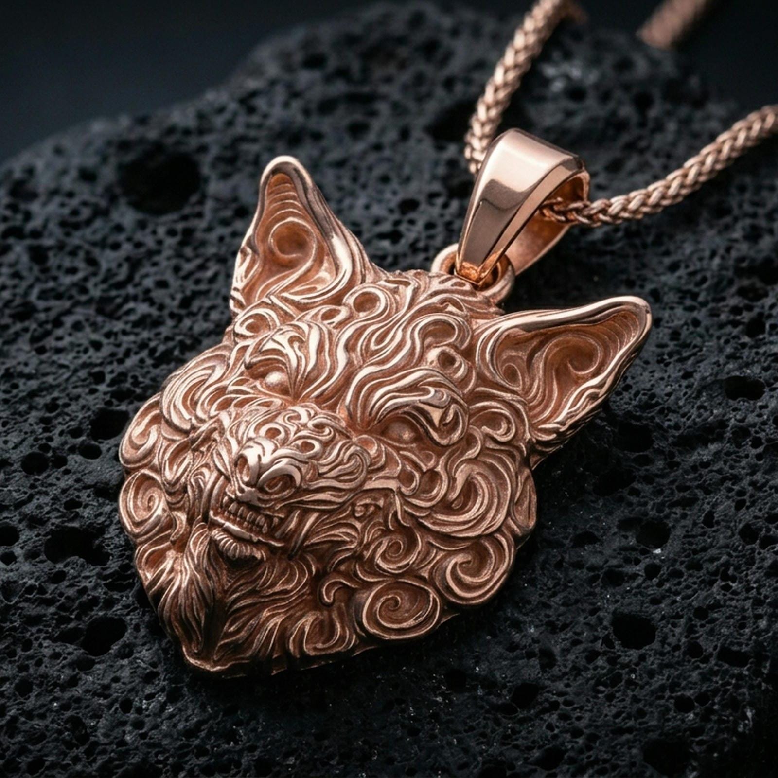 Rose gold plated wolf pendant with detailed animal face, flowing carved fur relief, and dramatic head silhouette resting on volcanic rock in an elegant close-up product presentation