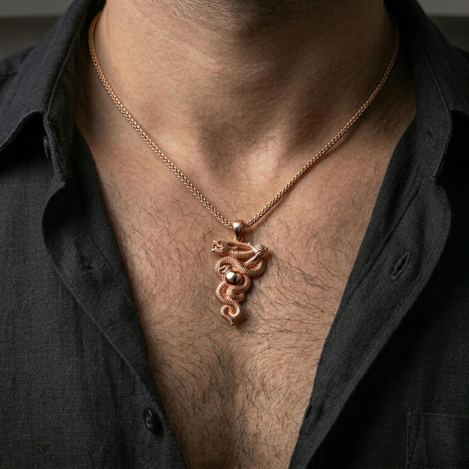 Rose gold plated snake pendant with wrapped serpent silhouette, scale relief, and apple detail worn on the neck in a refined lifestyle shot with a warm and distinctive presentation