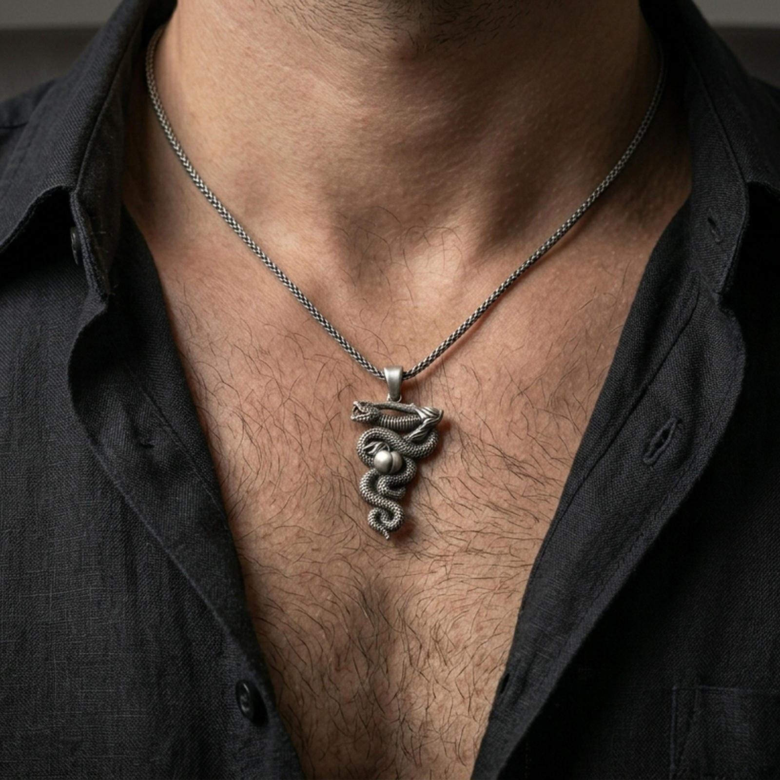 Oxidized serpent pendant with coiled snake and apple motif worn on the neck in a lifestyle jewelry shot, styled against the chest for a bold and symbolic statement look
