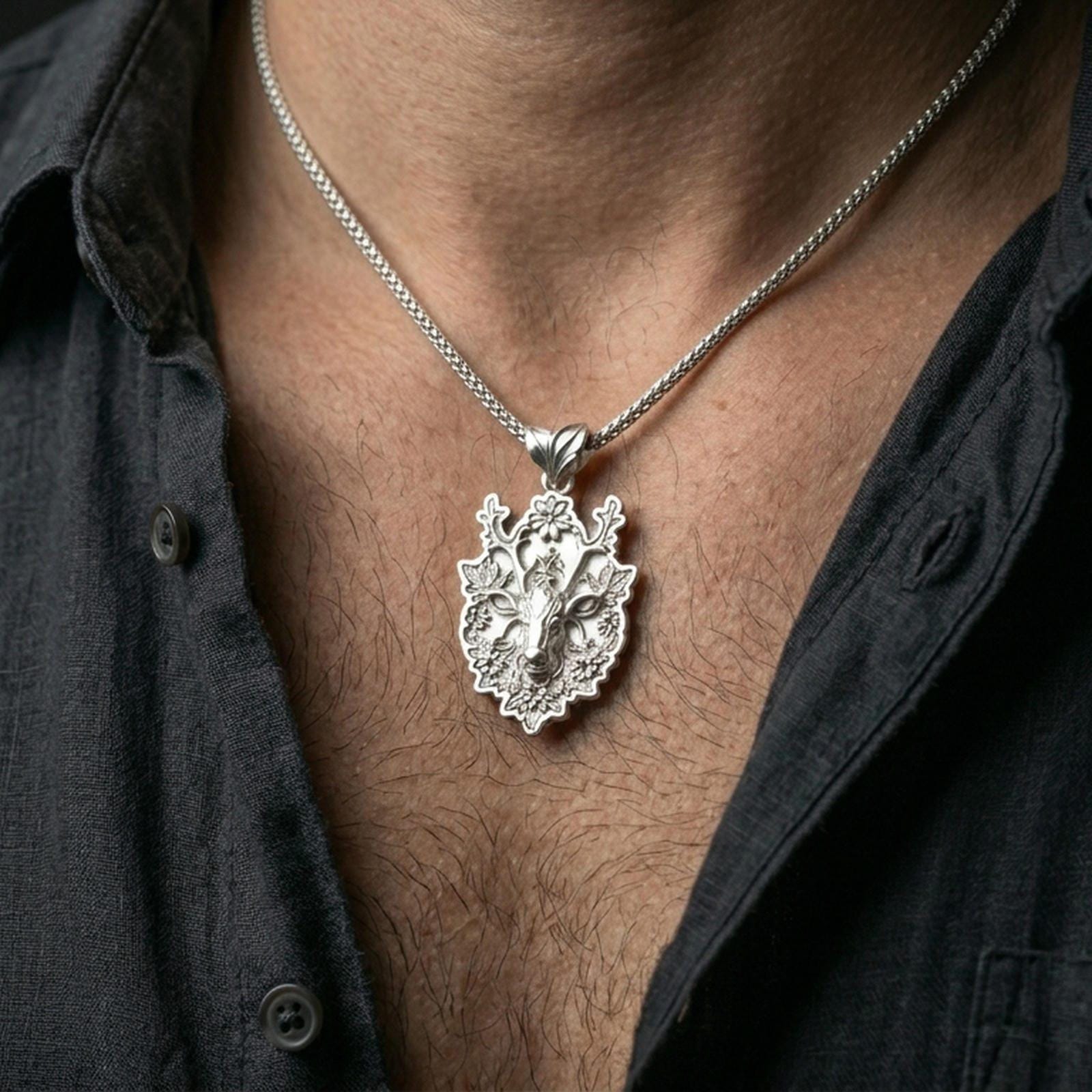 Polished silver stag necklace with sculpted deer face and botanical antler details worn on the neck in a close lifestyle frame, highlighting the woodland artistry and intricate relief