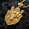 Load image into Gallery viewer, Gold plated deer pendant with ornate floral motifs, detailed antler design, and artistic forest-inspired animal form showcased on black volcanic rock in a refined macro jewelry image
