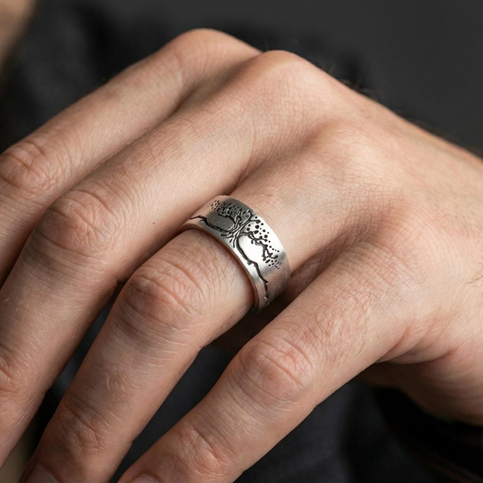 Oxidized sterling silver Tree of Life ring worn on finger, deep contrast in the engraving for a bold symbolic look, lifestyle hand close-up.