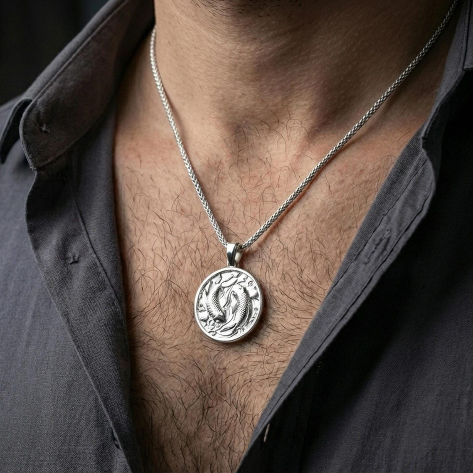 Polished silver koi necklace with yin yang-inspired fish design worn on the neck in a close lifestyle frame, highlighting the circular medallion shape and detailed aquatic relief