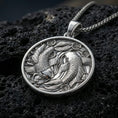 Load image into Gallery viewer, Polished silver koi necklace with detailed fish scales, circular yin yang arrangement, and layered aquatic floral motifs placed on textured volcanic rock in a premium studio product shot
