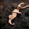 Load image into Gallery viewer, Rose gold plated geometric seahorse necklace with clean angular folds, elegant marine shape, and contemporary minimalist styling resting on volcanic rock in an elegant close-up product presentation
