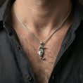 Load image into Gallery viewer, Polished silver seahorse necklace with geometric folded silhouette worn on the neck in a close lifestyle frame, highlighting the angular origami form and minimalist marine design
