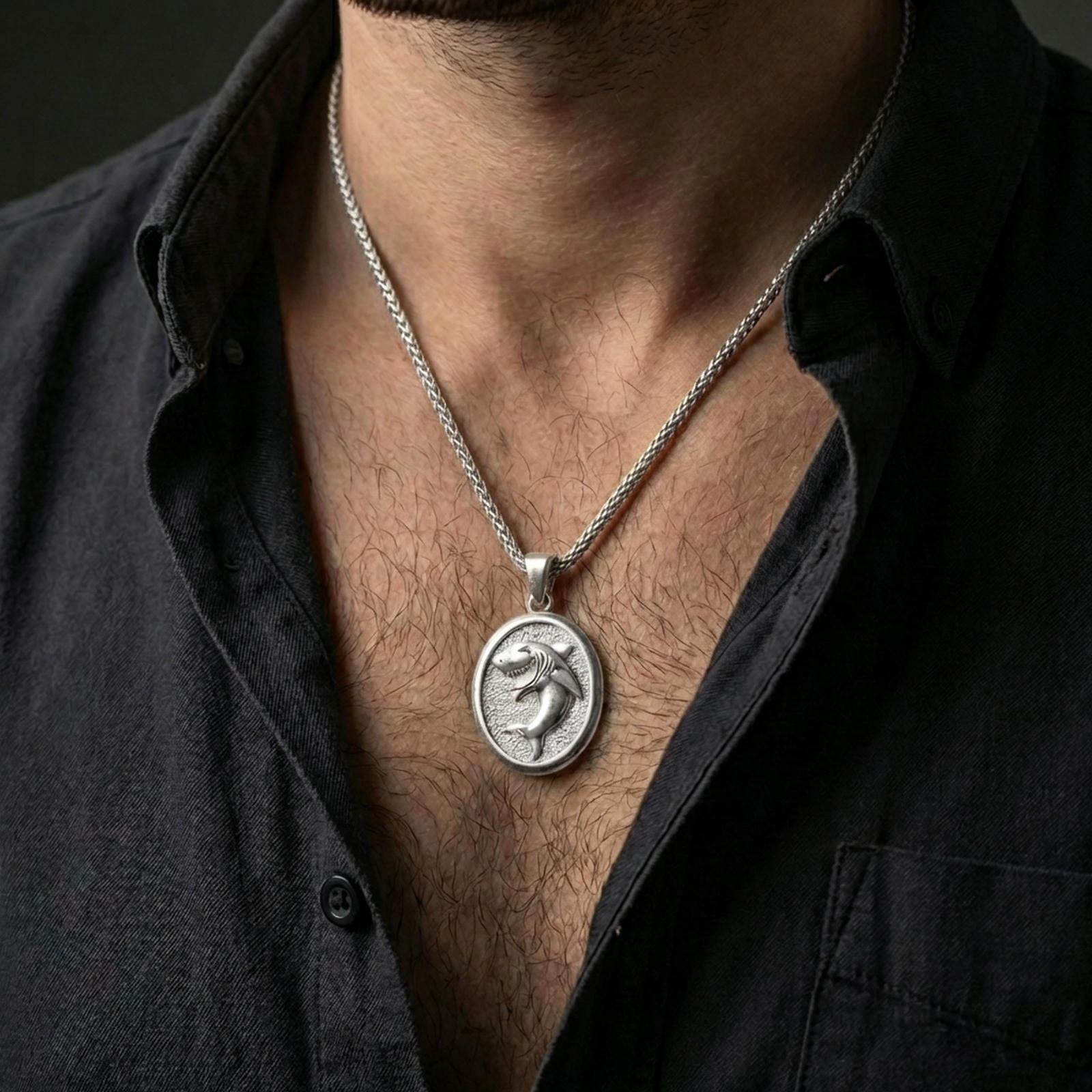 Polished silver shark necklace with open-mouth shark design worn on the neck in a close lifestyle frame, highlighting the oval medallion shape and detailed marine relief