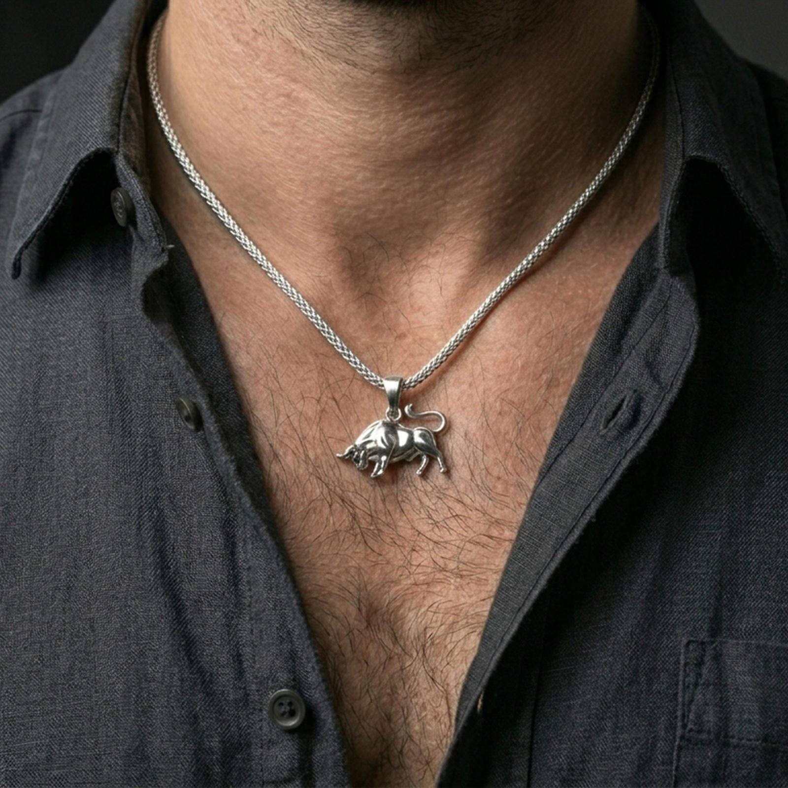 Polished silver bull necklace worn on the neck in a close lifestyle frame, highlighting the sculpted body detail and dynamic animal silhouette