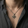 Load image into Gallery viewer, Oxidized snake knot pendant with intertwined serpents worn on the neck in a lifestyle jewelry shot, styled against the chest for a bold and symbolic statement look
