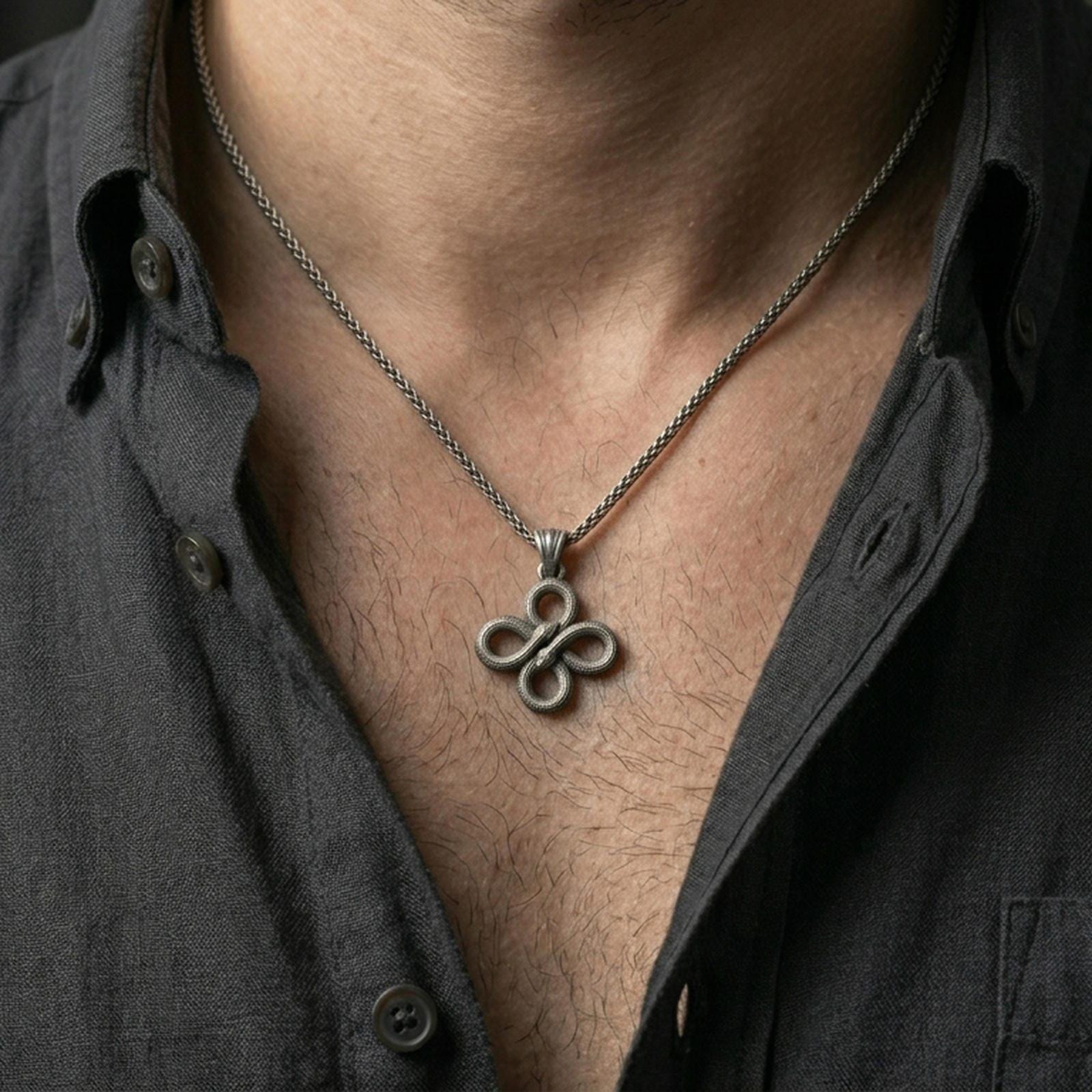 Oxidized snake knot pendant with intertwined serpents worn on the neck in a lifestyle jewelry shot, styled against the chest for a bold and symbolic statement look