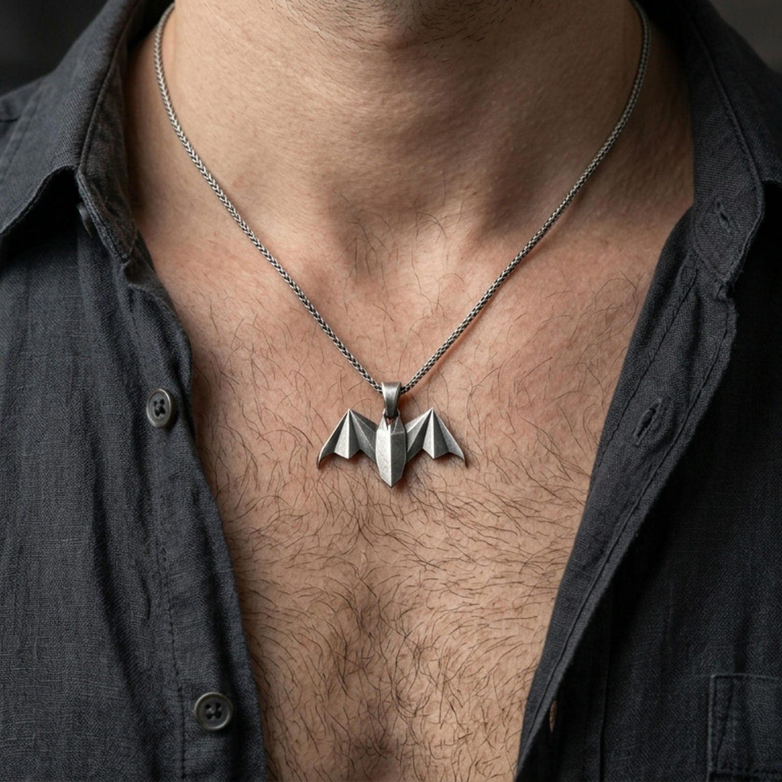 Oxidized origami bat pendant worn on the neck in a lifestyle jewelry shot, styled against the chest for a bold and gothic statement look