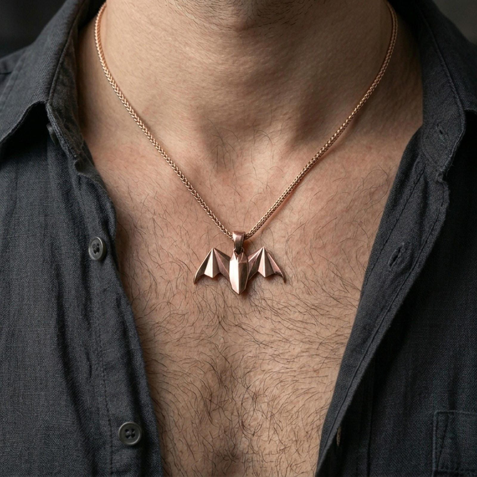 Rose gold plated bat necklace with minimalist folded form and pointed wing silhouette worn on the neck in a refined lifestyle shot with a warm and distinctive presentation