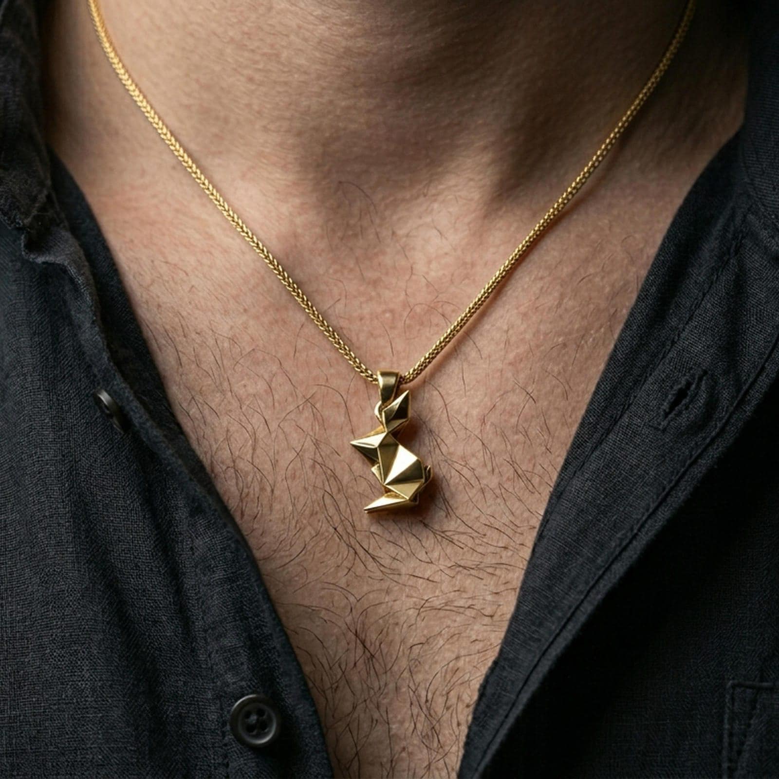 Gold plated origami rabbit pendant with angular minimalist design worn on the neck in a premium lifestyle composition with refined contemporary jewelry styling