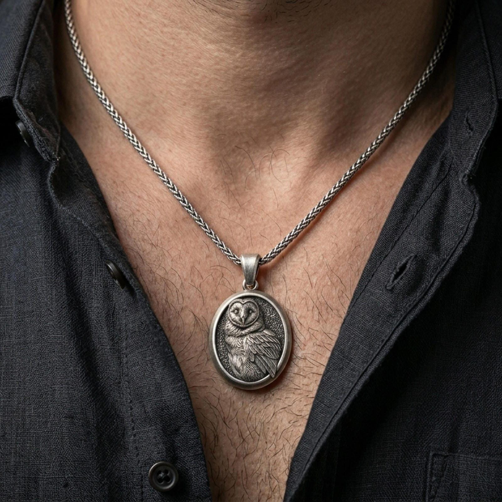 Oxidized owl pendant with engraved feather details worn on the neck in a lifestyle jewelry shot, styled against the chest for a symbolic and nature-inspired statement look