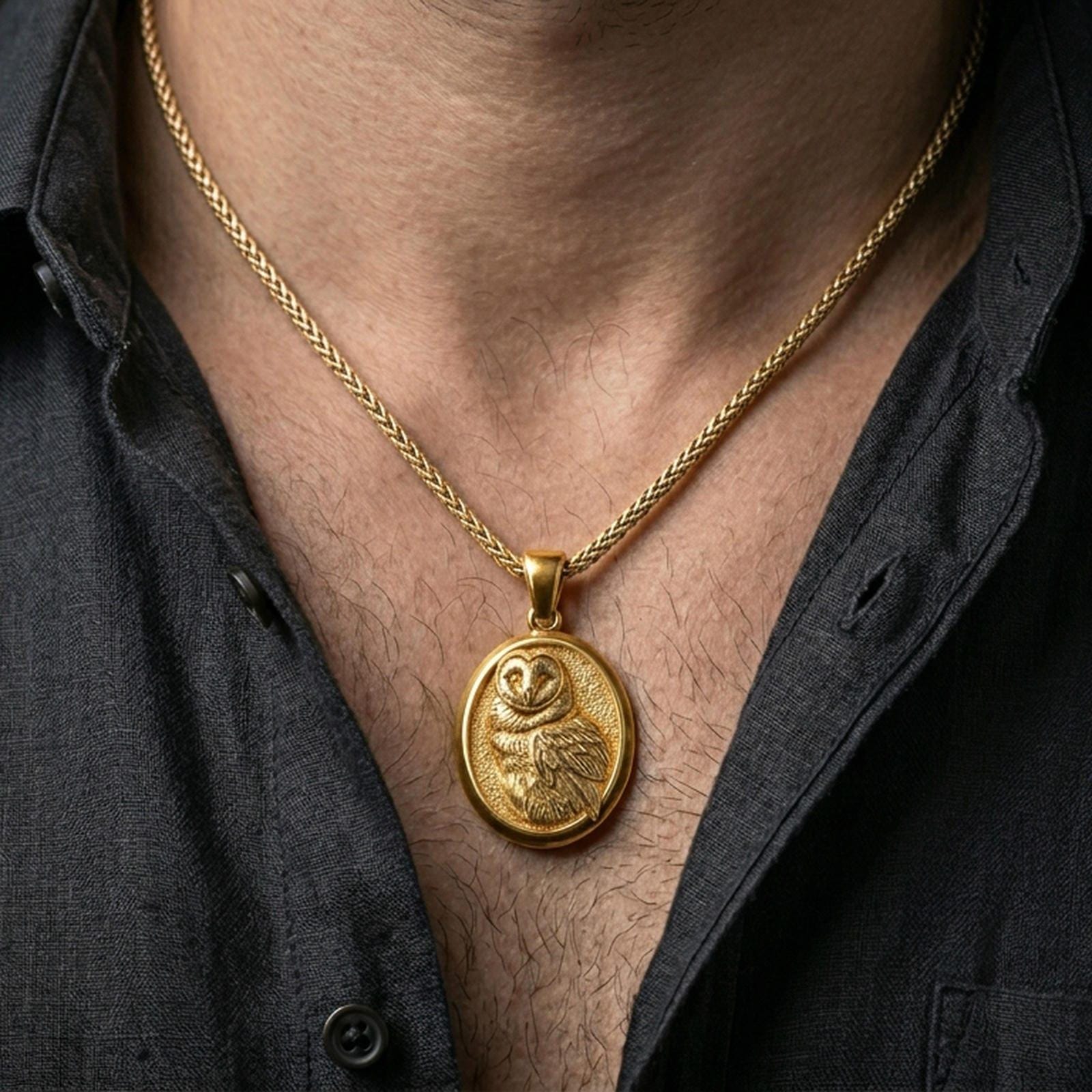 Gold plated owl pendant with intricate plumage and oval symbolic design worn on the neck in a premium lifestyle composition with graceful bird-inspired jewelry styling