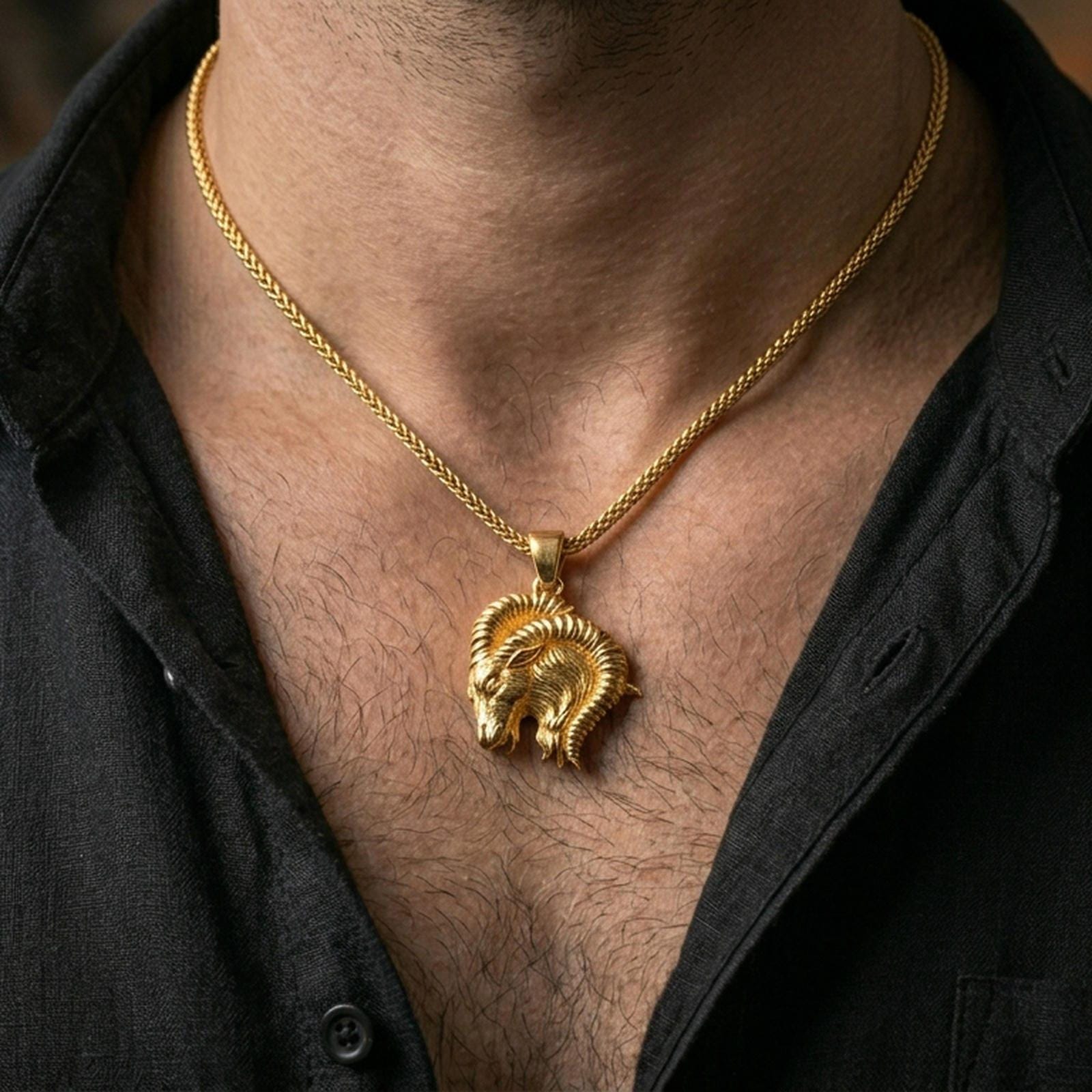 Gold plated Aries pendant with bold ram head motif and sweeping horn silhouette worn on the neck in a premium lifestyle composition with refined astrology jewelry styling