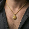 Load image into Gallery viewer, Gold plated twin wolf pendant with wolfpack motif, sculpted fur detailing, and round wilderness design worn on the neck in a premium lifestyle composition with strong animal-inspired jewelry styling
