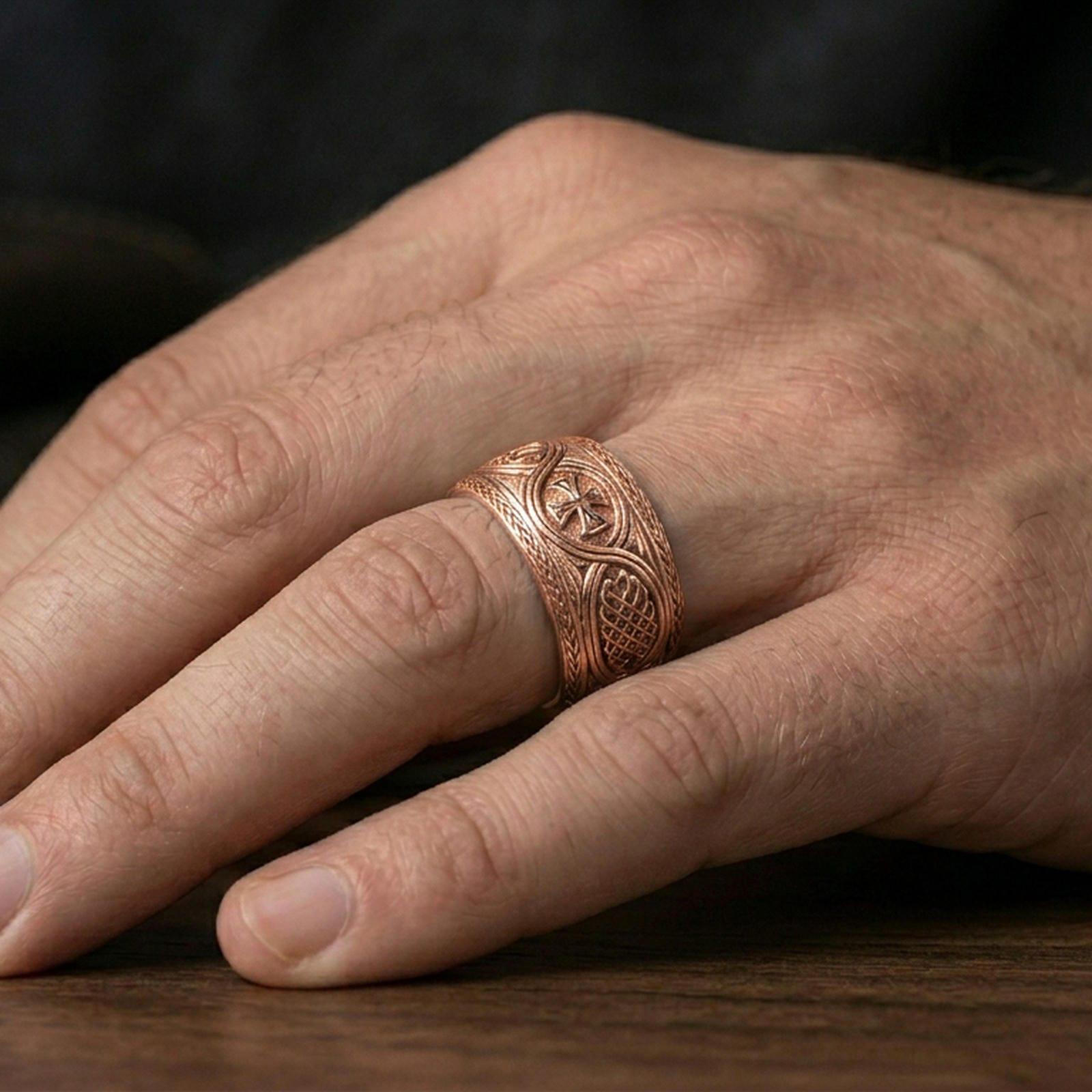 Rose gold plated Celtic weave iron cross ring worn on finger, refined warm glow with crisp knot engraving and smooth rounded edges.