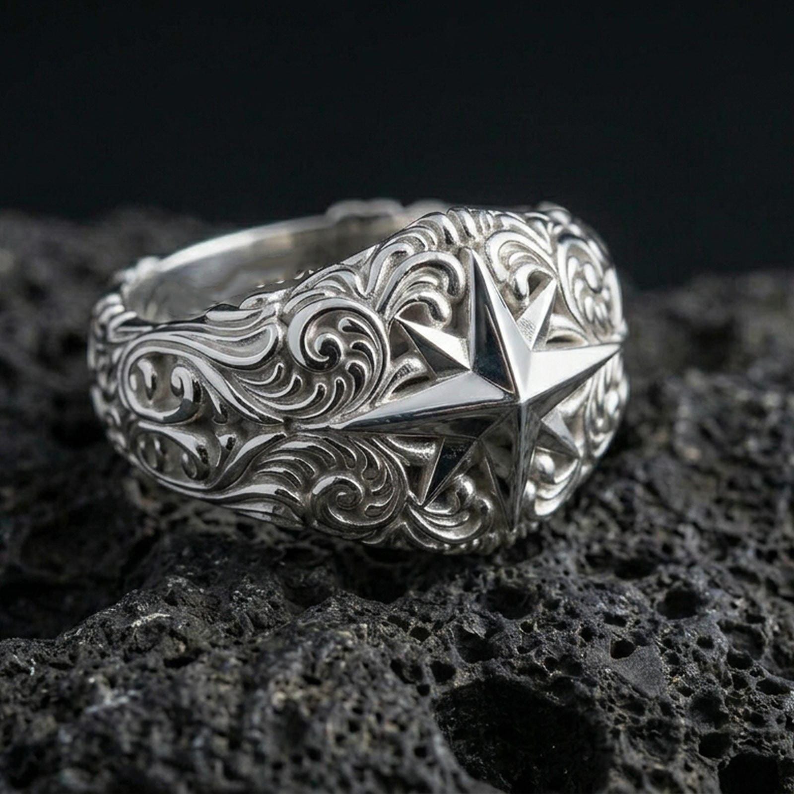 Polished silver North Star statement ring on volcanic rock, crisp eight-point star and engraved swirl relief captured in sharp macro detail.