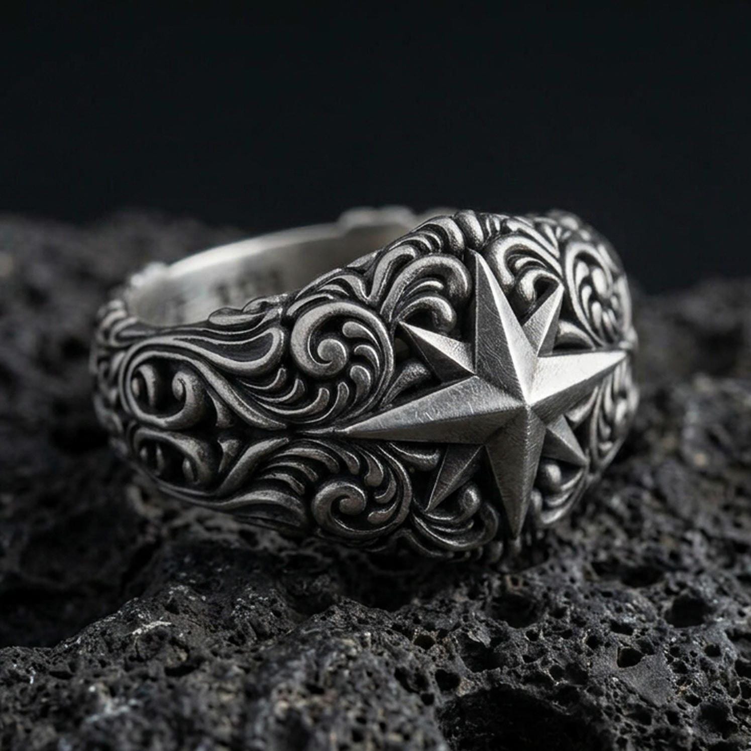 Oxidized sterling silver North Star signet ring on black volcanic stone, hand-carved compass star with deep shadowed scrollwork for bold contrast.