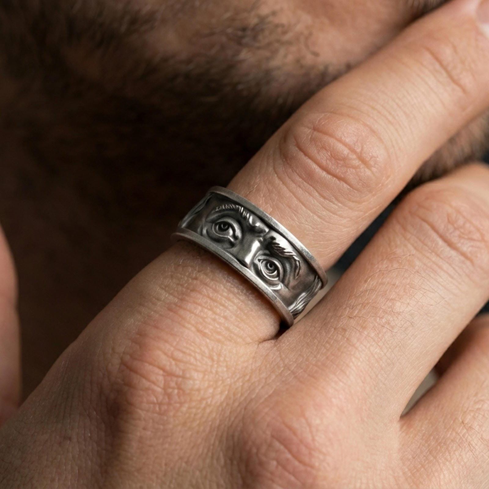 Oxidized sterling silver Benjamin Franklin eyes ring worn on finger, high-contrast antique look with bold portrait relief and statement presence.