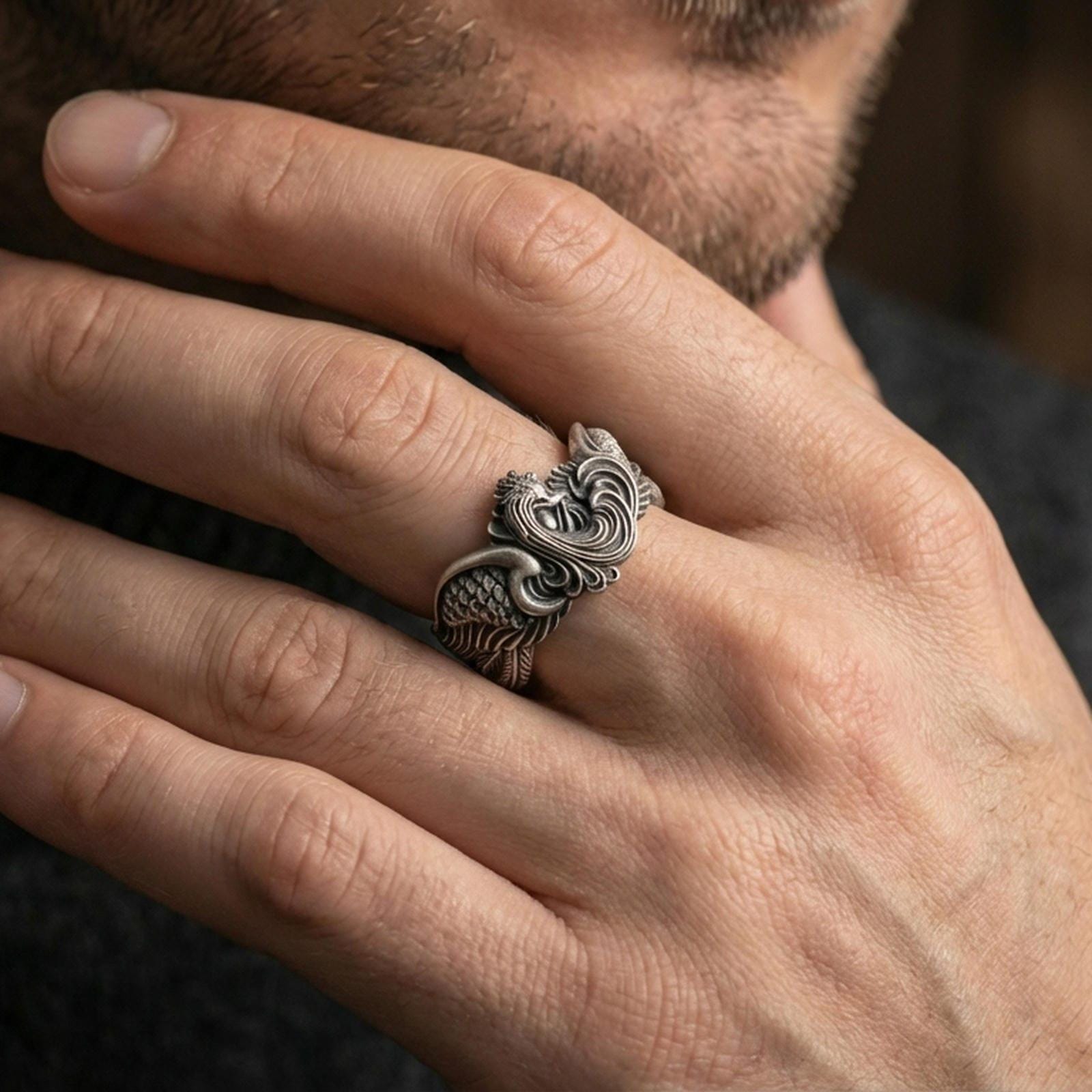 Oxidized sterling silver rooster ring worn on a finger, showcasing the dimensional rooster head and feathered band texture.