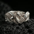 Load image into Gallery viewer, 925 silver rooster statement ring on black volcanic stone, polished silver highlights outlining the sculpted wings and tail curls.
