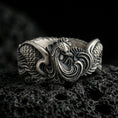 Load image into Gallery viewer, Sterling silver rooster ring photographed on volcanic rock with oxidized contrast emphasizing the carved feathers and bold crest detail.
