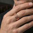 Load image into Gallery viewer, Rose gold plated fleur de lis band ring on a finger, elegant metallic glow with clear fleur de lis detailing and smooth edges.
