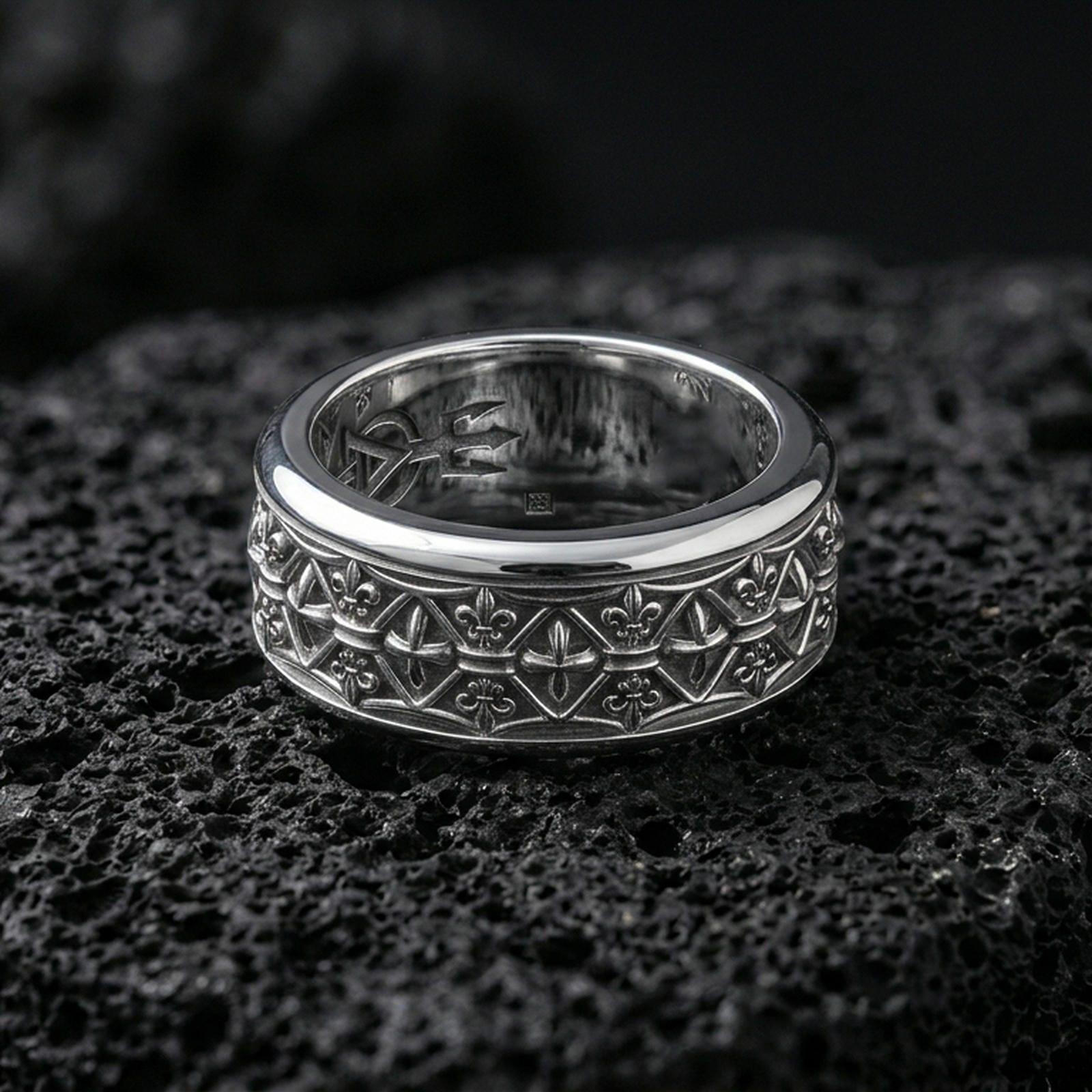 925 silver fleur de lis ring on black volcanic stone, polished silver rim framing the engraved lattice and fleur details.
