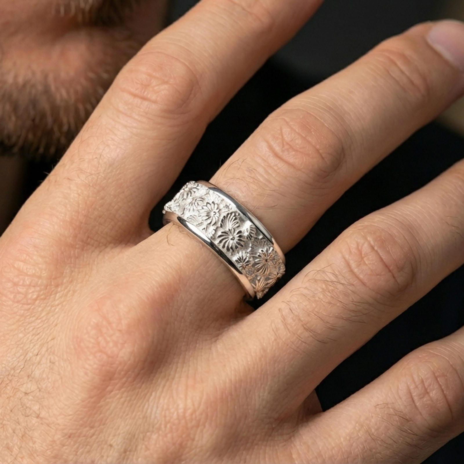 Polished silver floral spinner ring on a finger, clean shine along the rim with detailed daisy blossoms across the band.