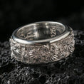 Load image into Gallery viewer, 925 silver daisy spinning band on black volcanic stone, polished silver rim framing the detailed floral pattern around the ring.
