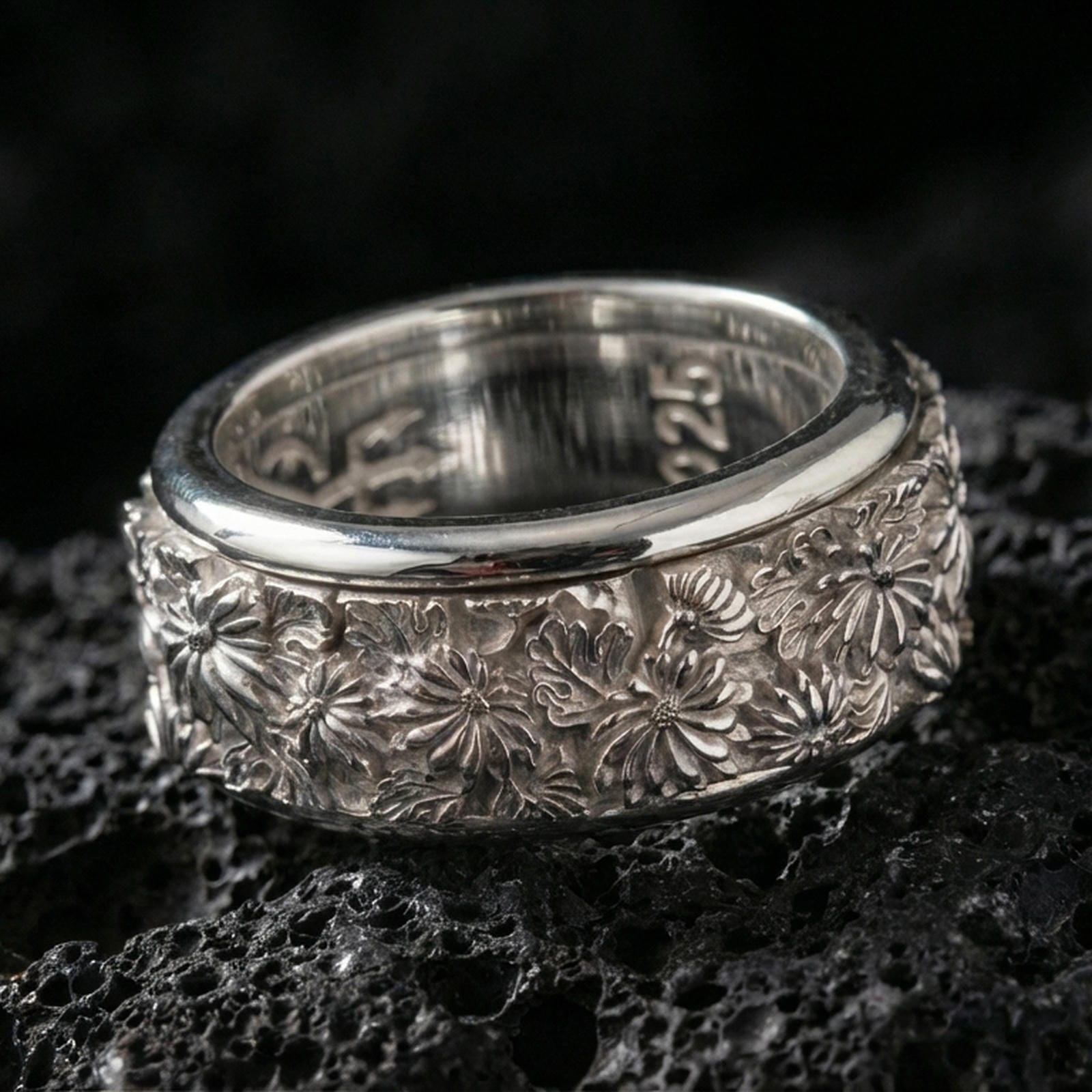 925 silver daisy spinning band on black volcanic stone, polished silver rim framing the detailed floral pattern around the ring.