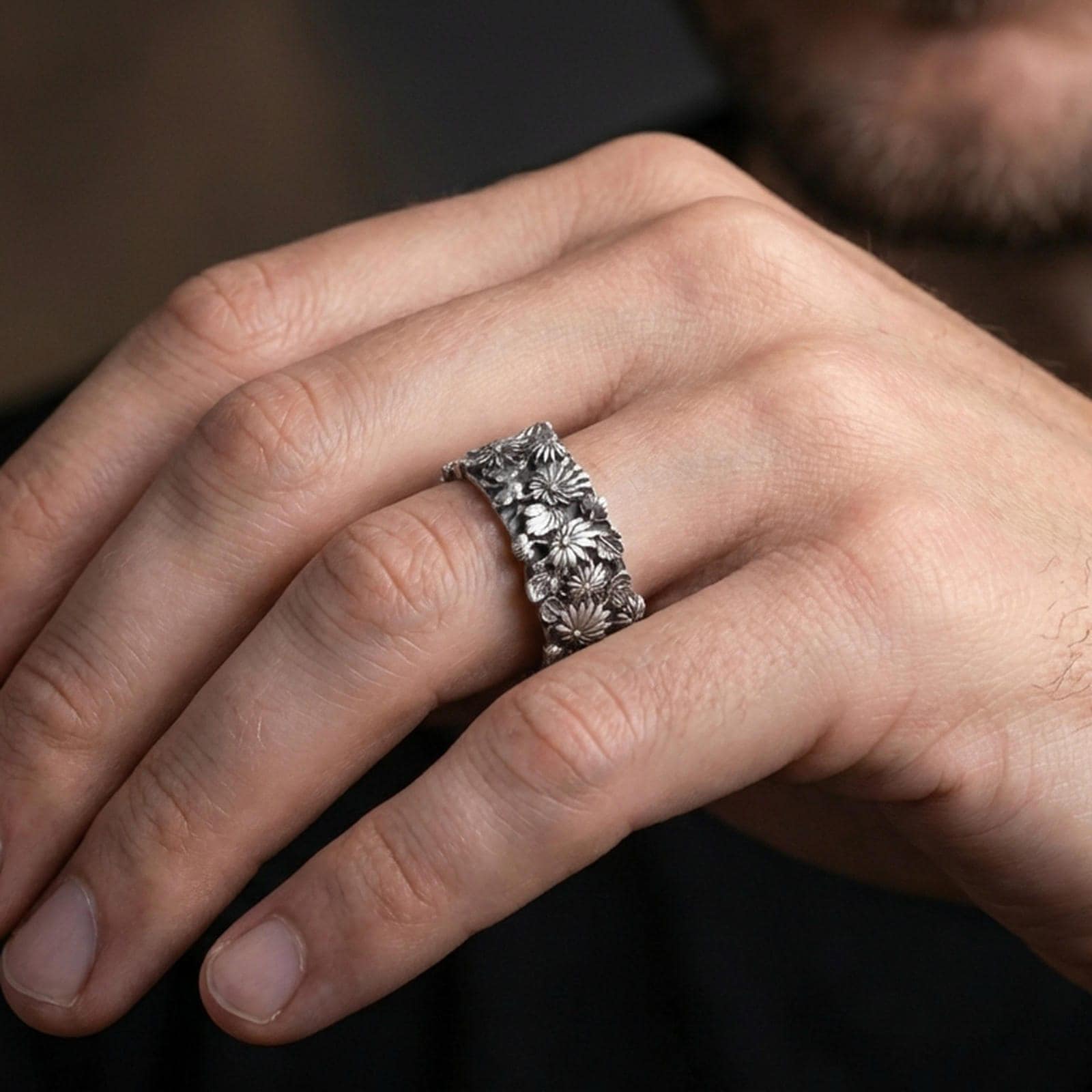 Oxidized sterling silver floral ring worn on a finger, showcasing the raised flower cluster texture and artisan carving depth.
