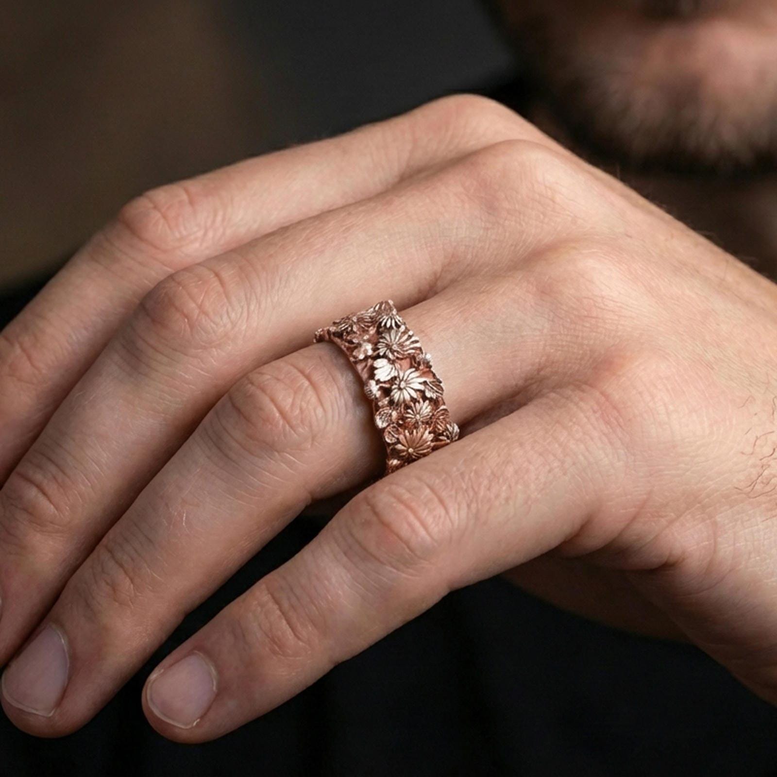 Rose gold plated daisy relief ring on a finger, elegant metallic glow with sculpted flowers and a smooth rounded band.
