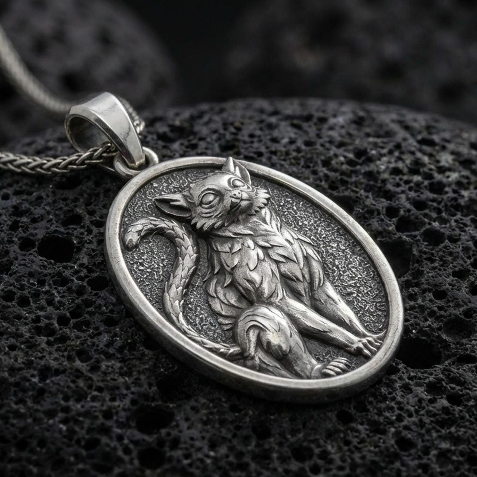 A 925 sterling silver cat pendant on black volcanic stone, with an oxidized finish highlighting the seated feline relief.