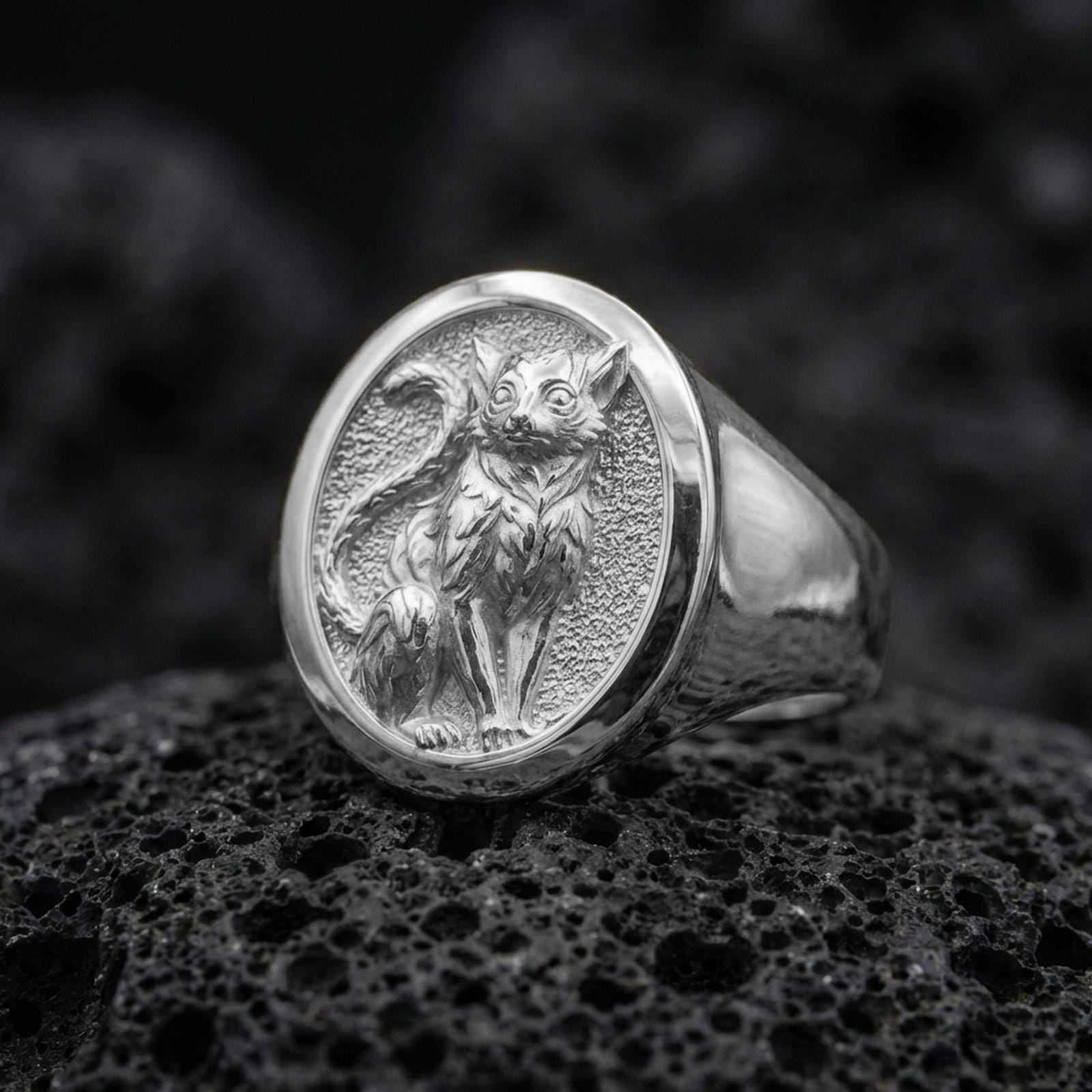 A 925 sterling silver feline signet ring on black volcanic rock, polished silver highlights showing the sculpted cat details.