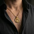 Load image into Gallery viewer, A gold plated Perseus and Medusa necklace worn on the neck, heroic warrior coin pendant with Greek key border.
