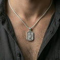 Load image into Gallery viewer, Saint Michael dog tag necklace on a model’s neck, close-up of the archangel relief with the spear and shield clearly visible.
