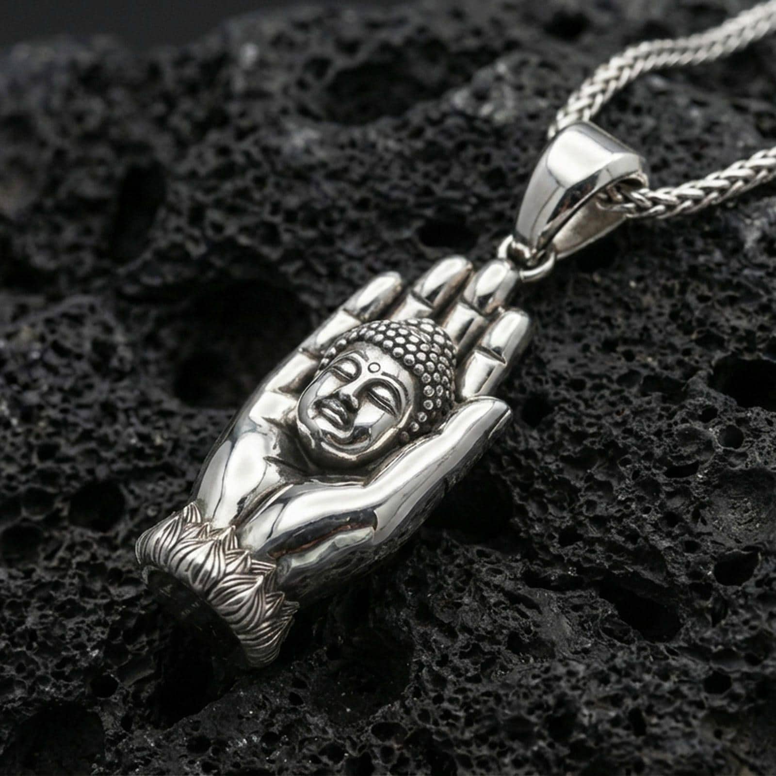 925 sterling silver Buddha hand pendant on volcanic rock with a clean polished shine highlighting the serene face and hand contours.