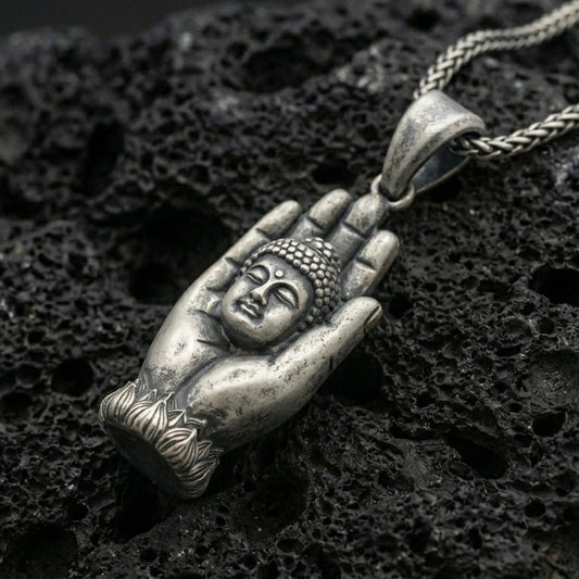 Buddha in protective hand pendant on black volcanic stone with deep oxidized contrast and vintage patina detail.