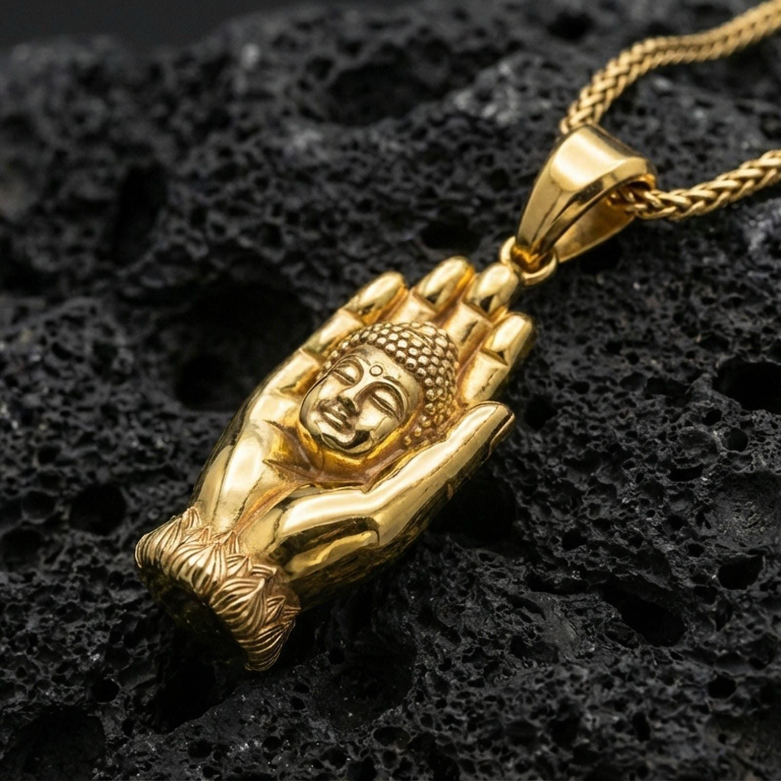 Buddha in hand pendant on volcanic stone with a bright gold plated look, emphasizing the lotus base and sculpted relief.