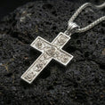Load image into Gallery viewer, Polished silver cross pendant with delicate rose motifs and framed edges placed on textured volcanic rock in a premium studio product shot
