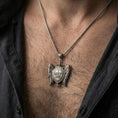 Load image into Gallery viewer, Oxidized Saint Michael shield pendant with angel wings and sword worn on the neck in a lifestyle jewelry shot, styled against the chest for a strong devotional look
