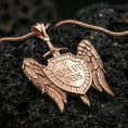 Load image into Gallery viewer, Rose gold plated Christian protection pendant with angel wing motif, sword, and Quis Ut Deus shield showcased on volcanic rock in an elegant close-up presentation
