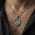 Load image into Gallery viewer, Oxidized angel medal pendant worn on the neck in a lifestyle jewelry shot, styled against the chest for a devotional and timeless look
