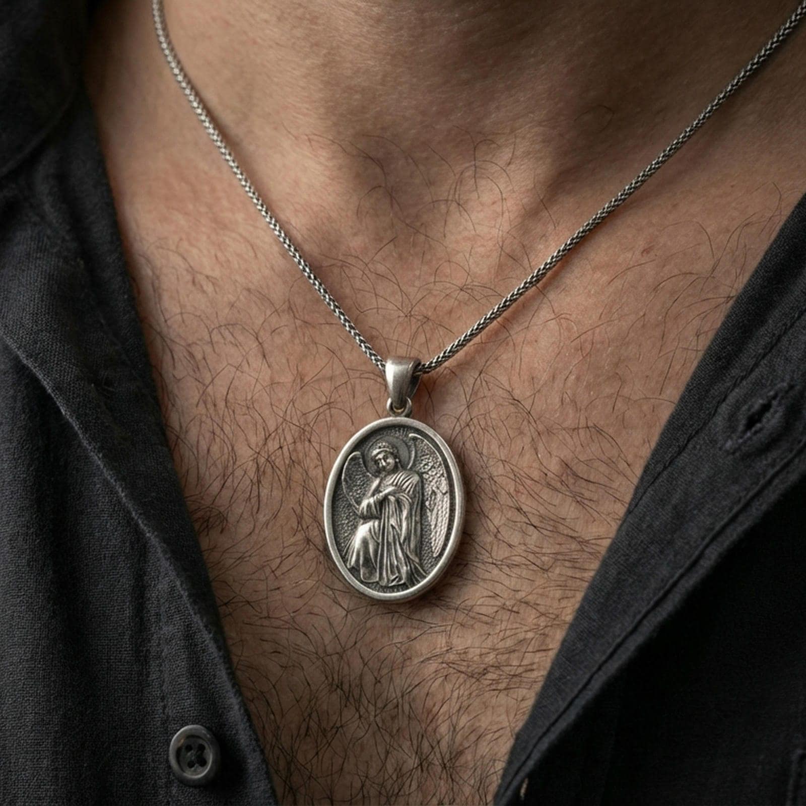 Oxidized angel medal pendant worn on the neck in a lifestyle jewelry shot, styled against the chest for a devotional and timeless look