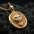 Load image into Gallery viewer, Gold plated gorilla pendant with intense roaring ape expression, textured fur detailing, and strong oval silhouette showcased on black volcanic rock in a refined macro jewelry image
