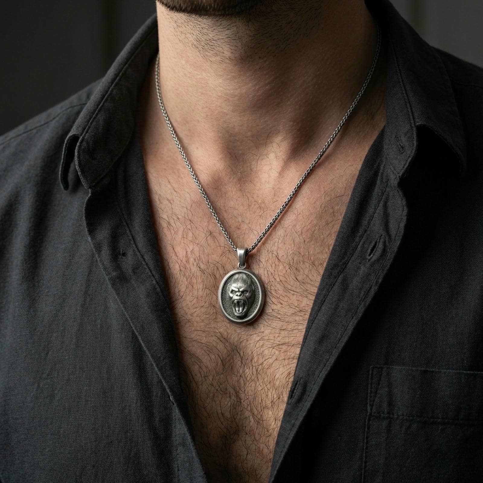 Oxidized roaring gorilla pendant with fierce ape face and open-mouth expression worn on the neck in a lifestyle jewelry shot, styled against the chest for a bold and primal statement look